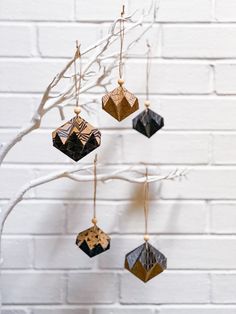 an ornament hanging from a tree branch on a white brick wall in the winter