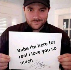 a man holding up a sign that says babe i'm here for real i love you so much