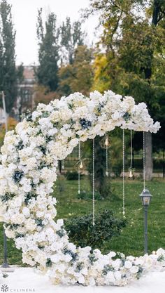 an outdoor wedding ceremony with white flowers and greenery on the arch, hanging from chains