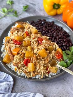 a plate filled with rice, beans and chicken on top of a table next to oranges