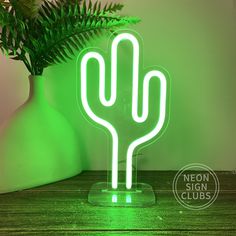 a neon green cactus lamp sitting on top of a wooden table next to a potted plant