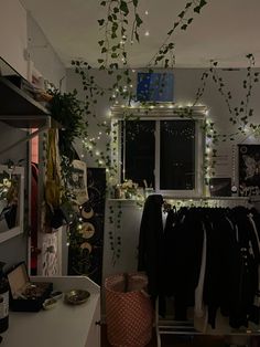 a room filled with lots of clothes and plants hanging from it's windowsill