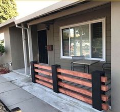 a small house with a wooden fence around the front porch and table on the side