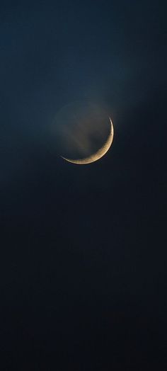 the moon is seen in the dark sky with some clouds around it, as well as an object that looks like a crescent