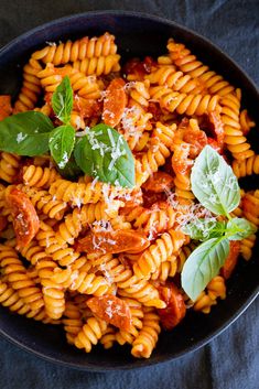 a bowl filled with pasta and sauce on top of a blue cloth next to a fork