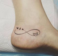 a tattoo on the foot of a woman with two birds flying over an infinite love knot