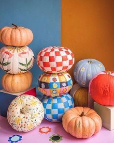 pumpkins and gourds are stacked on top of each other in front of a blue wall