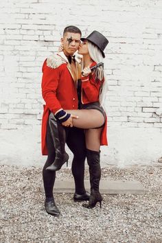 a man and woman dressed up in costume kissing each other on the cheek while standing next to a white brick wall