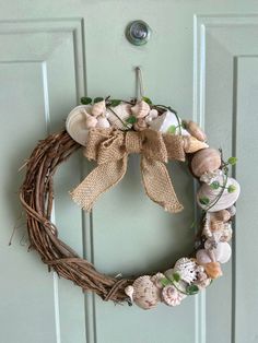 a wreath with seashells and burlocks is hanging on the front door