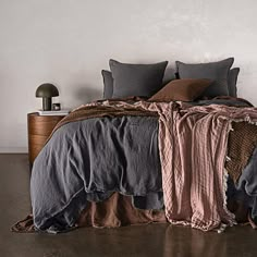 an unmade bed with grey and brown linens