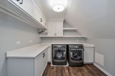 an empty laundry room with two washers and dryer in the corner, next to white cabinets