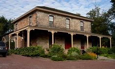 a car parked in front of an old brick house with porches and columns on the roof