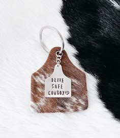 the drive safe cowboy keychain is on top of a cowhide fur background