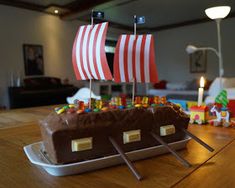 there is a cake that looks like a boat with legos on it and candles in the background