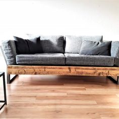 a gray couch sitting on top of a hard wood floor next to a white wall