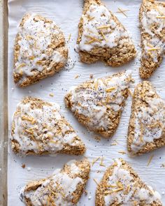 six scones covered in white icing and sprinkled with orange zest