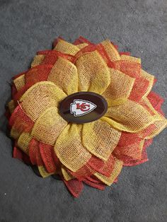 a kansas chiefs pin sitting on the ground next to a piece of fabric with a football logo on it