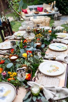 the table is set with plates and flowers on it, along with other place settings