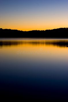 the sun is setting over a lake with mountains in the background royalty photo - illustration