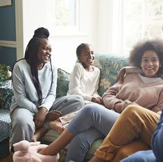 four women sitting on a couch laughing together