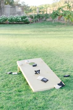 a cornhole game is set up in the middle of a grassy field with other items scattered around it