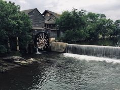 an old mill with water coming out of it's gates and into the river