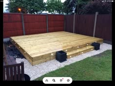 a large wooden deck in the middle of a yard with lights on it and some trash cans