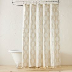 a bath tub sitting next to a shower curtain with circles on it's side