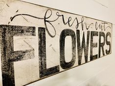 there is a sign that says flowers on the side of the wall with words above it