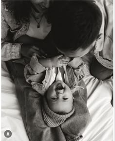 a black and white photo of a young boy laying on his mother's back