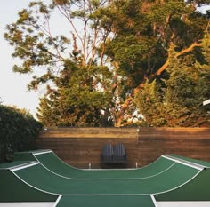 a tennis court with a chair on the side and trees in the backgroud