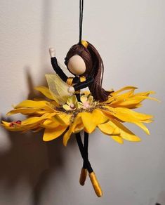 a doll hanging from a string with yellow flowers on it's back and legs