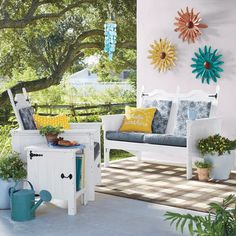 a white bench sitting on top of a patio next to potted plants and sunflowers