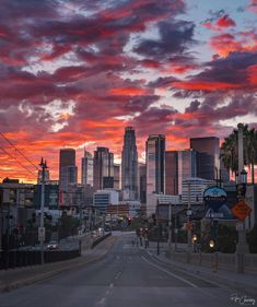 the sun is setting over a city with tall buildings and palm trees in the foreground