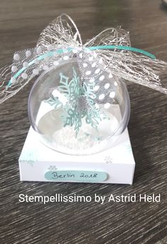 a glass ornament with snowflakes on it sitting on top of a wooden table