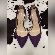 a pair of purple high heeled shoes sitting on top of a cow print rug