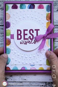 someone holding up a card with the words best wishes on it and a purple ribbon