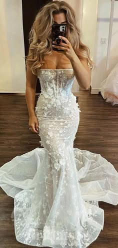 a woman taking a selfie in a wedding dress with her phone up to her face