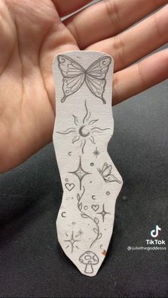 a hand holding a piece of paper with a butterfly on it's back and the outline of a woman's body