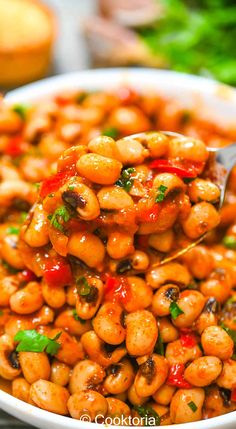 a spoon full of cooked chickpeas with red peppers and cilantro sauce