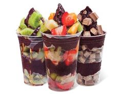 three plastic cups filled with different types of fruit and chocolates on top of each other