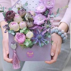 a woman holding a purple box with flowers in it