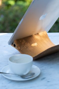 an apple computer sitting on top of a table next to a cup and saucer