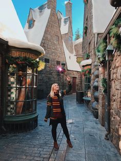 a woman standing in the middle of an alley way with buildings and lights on either side