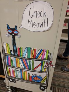 a book cart with a cat sitting on top of it and a sign that says check meow