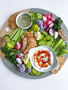 a platter filled with vegetables, dip and crackers