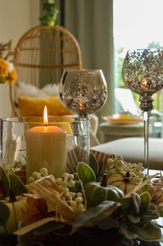 a candle is lit on a table with flowers and candlesticks in front of it