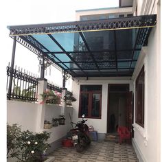 a motorcycle is parked in front of a house with a glass roof over the entrance