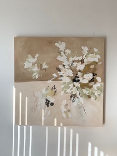 a painting hanging on the wall next to a white fence with flowers painted on it