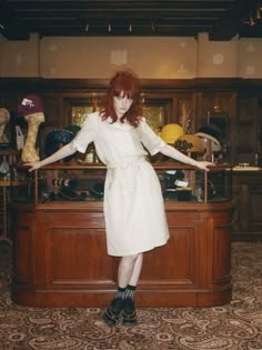 a woman standing in front of a counter with her arms out and hands outstretched to the side